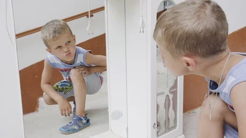 Boy clown and make faces in front of the mirror Stock Footage 94253106