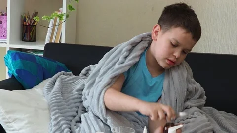 A boy with a cold is at home, being treated. medicines, throat and nose spray 库存影片 164471696