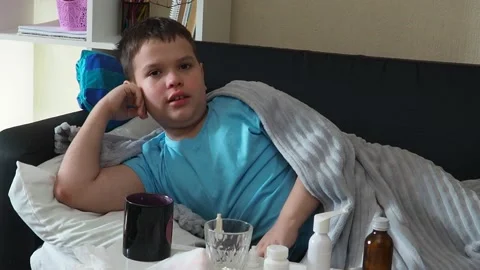 A boy with a cold is at home, being treated. medicines, throat and nose spray 库存影片 164471801