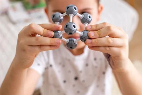 The boy collects a model of a silver molecule from a constructor using the Stock Photos