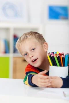 Boy with colored pencils at table Stock Photos