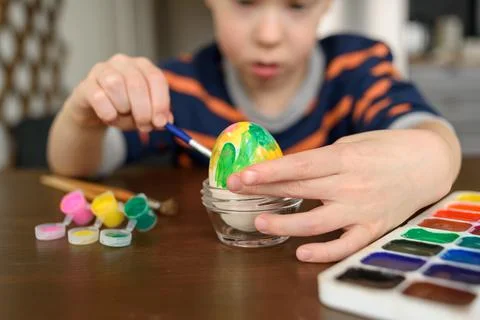 Boy coloring Easter egg Stock Photos