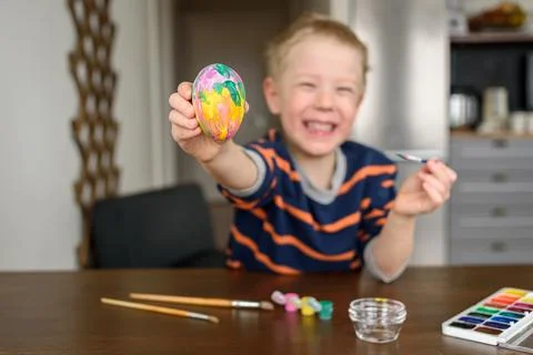 Boy coloring Easter egg Stock Photos