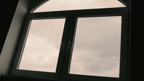 The boy comes to the window with a cloudy sky and looks at the street. Stock Footage 74609849