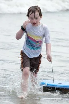 Boy coming out of the ocean waves with a boogy board Stock Photos