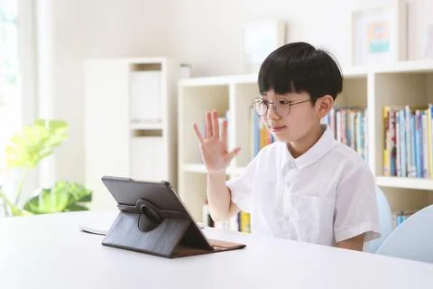 Boy communicating with teacher while teaching online video lessons at home Stock-Fotos