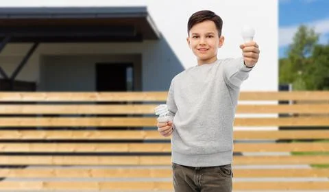 Boy comparing different light bulbs over house Stock Photos