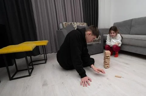 A boy concentrates deeply while maneuvering wooden blocks in a game, as a gir Fotos de archivo