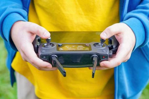 The boy controls the flight of the quadcopter using the remote control. Stock Photos