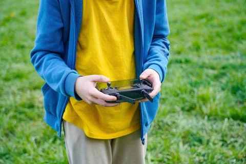 The boy controls the flight of the quadcopter using the remote control. 스톡 사진