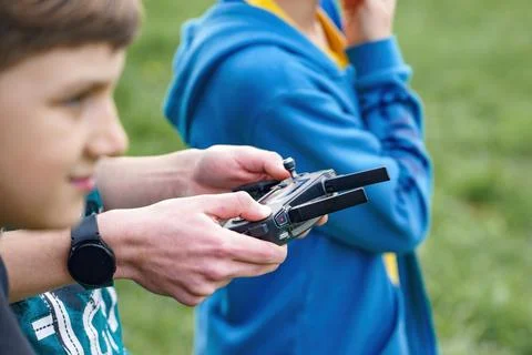 The boy controls the flight of the quadcopter using the remote control. Stock Photos