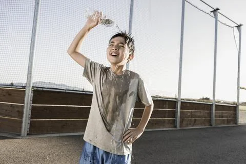 Boy cools off with water over his head. Stock Photos