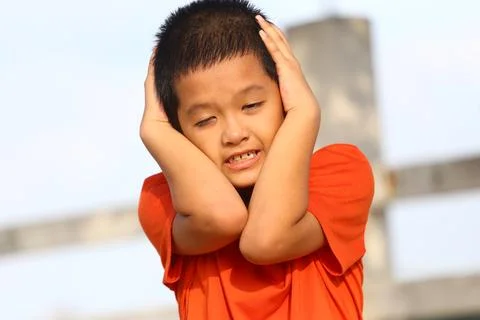 Boy Covering Ears in Outdoor Setting Stock Photos
