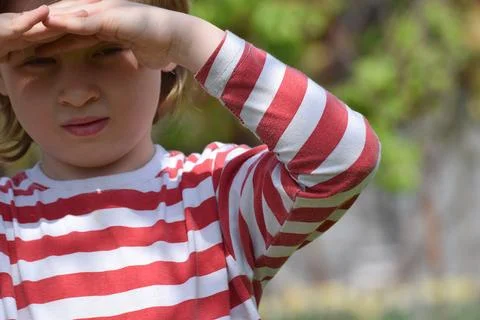 The boy covers himself with his hands from the sun. Stock Photos
