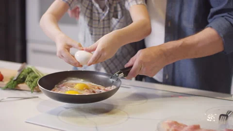 Boy Cracking Egg into Pan Held by his Father Stock Footage 131712760