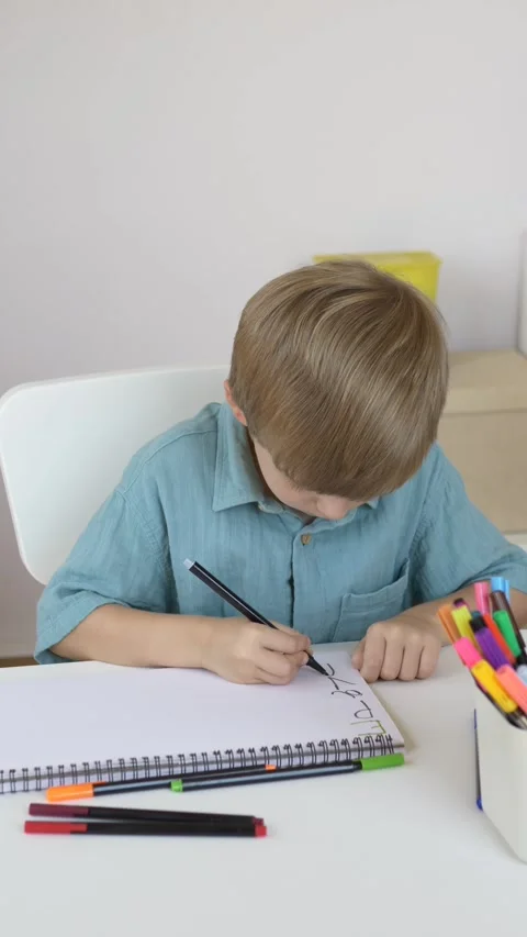 Boy creates colorful drawing using markers at home desk. Creative activity Stock Footage 345651986