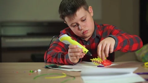The boy creates a plastic flower, uses a 3D pen. He learns creatively 库存影片 100387997