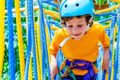 Boy crossing course high ropes element in adventure park outdoor. Concept Stock Photos