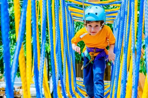 Boy crossing course high ropes element in adventure park outdoor. Concept Stock Photos