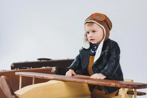 The boy is crying in a leather jacket and a pilot's hat, a wooden plane, brow Stock Photos