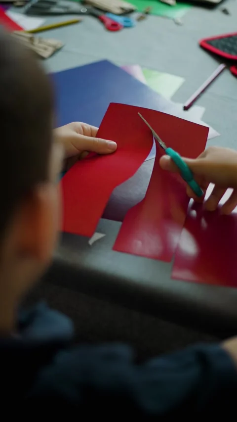 Boy Cutting Red Paper With Scissors Vertical Video Slow Motion Video stock 343451501
