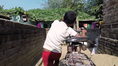 Boy cycles and pushes his bike through village alley, passing woman Stock Footage 87440962
