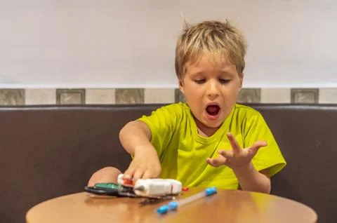 Boy damaged burned finger while doing DIY toys out of recycled materials plastic Stock Photos