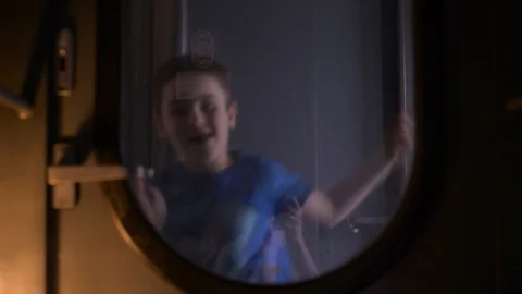 Boy dances in train between cars,operator is visible in reflection of glass. Video stock 128241706