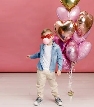 Boy dancing, smiling and having fun near  big branch of pink heart-shaped bal Stock Photos