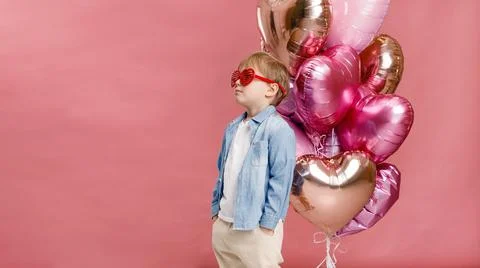 Boy dancing, smiling and having fun near  big branch of pink heart-shaped bal Stock Photos
