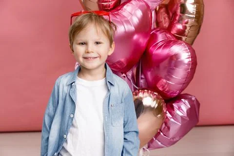 Boy dancing, smiling and having fun near  big branch of pink heart-shaped bal Stock Photos