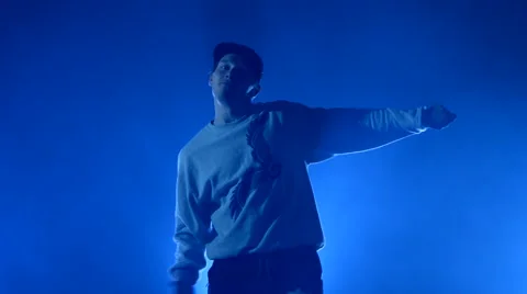 Boy dancing in a smoke on a blue background Stock Footage 63083509