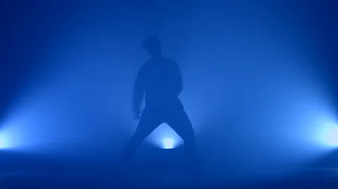 Boy dancing in a smoke on a blue background Stock Footage 63088408