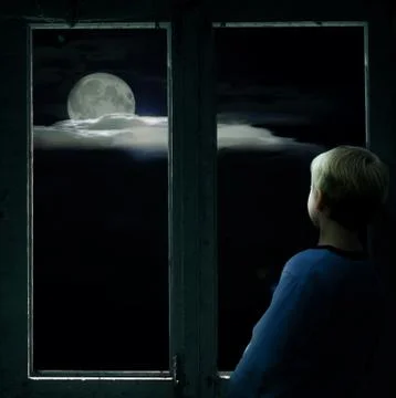 Boy in the dark window looking at the bright full moon Stock Photos