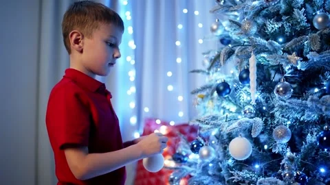 The boy decorates the Christmas tree, clings to the white ball. Stock Footage 258471884