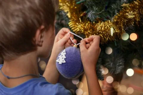 Boy decorates Christmas tree with creative baubles. Close-up Foto stock