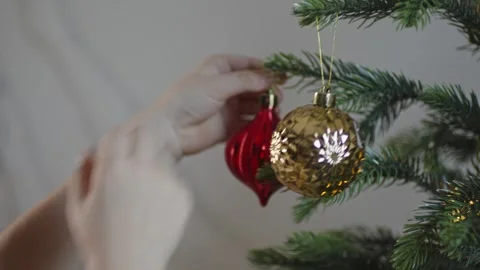 Boy decorates a Christmas tree by hanging Christmas toy balls in the room Video stock 291606806