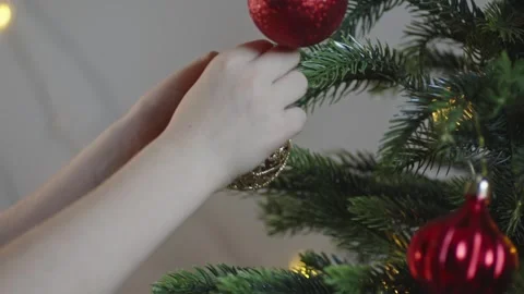 Boy decorates a Christmas tree by hanging Christmas toy balls in the room Video stock 291606993