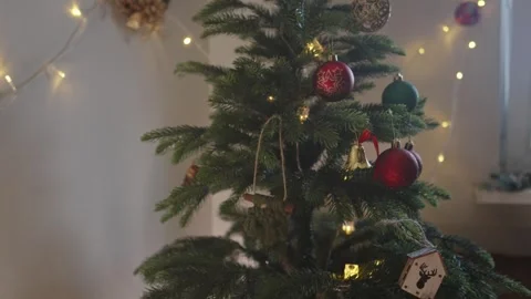 Boy decorates a Christmas tree by hanging Christmas toy balls in the room Stock Footage 291608319