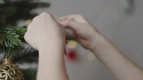 Boy decorates a Christmas tree by hanging Christmas toy balls in the room Stock Footage 291610390