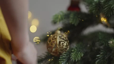 Boy decorates a Christmas tree by hanging Christmas toy balls in the room Stock Footage 291610561