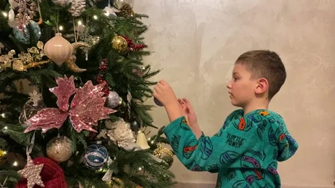 The boy decorates christmas tree at home Stock Footage 167202142