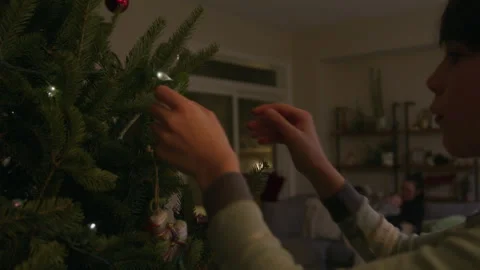 Boy decorates indoor christmas tree for holiday season as mother and other .. Stock Footage 345535133