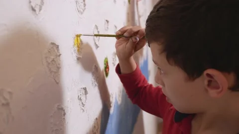 Boy decorating a white wall with paint Stock Footage 131556382