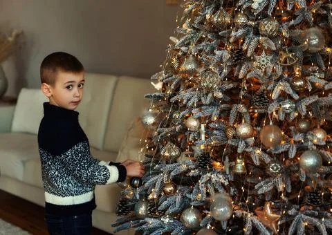 A boy decorating xmas tree in the evening at home. Serious work-focused child Foto stock