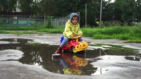 A boy in a denim jacket sits on a toy car, a girl roller-skates, happy children, Stock Footage 271518121