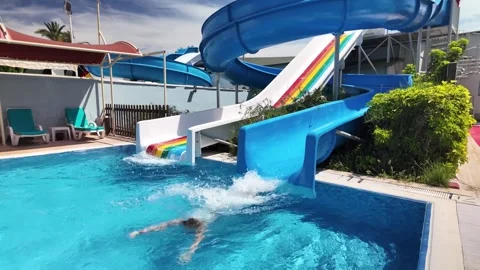 Boy descends from water slide into pool in water park Video stock 279054170