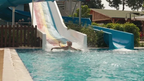 Boy descends from water slide into pool in water park Video stock 285601341