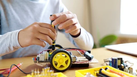 The boy designs an electronic toy model. Screws the missing screw in the circuit Stock Footage 93105283