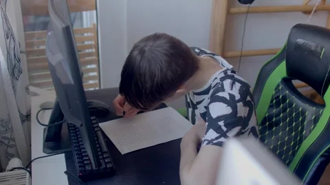 A boy at a desk uses a computer and paper, blending creativity Stock-Footage 311205324